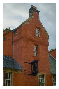 Abbot House front view, showing part of a red-coloured stone building with a black sign showing the name.